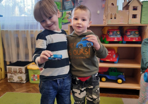 Chłopcy pozują do zdjęcia z samochodzikami