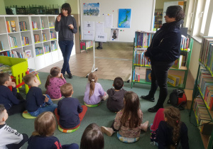 Dzieci siedzą na dywanie i słuchają jak Pani z biblioteki opowiada o Japonii